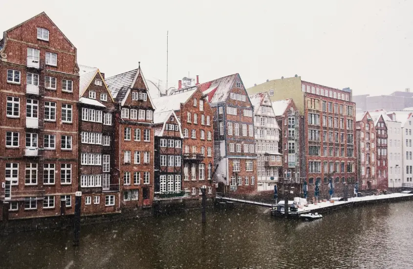 Prédios históricos de tijolos em Hamburgo cobertos de neve, à beira do canal, com um ar invernal