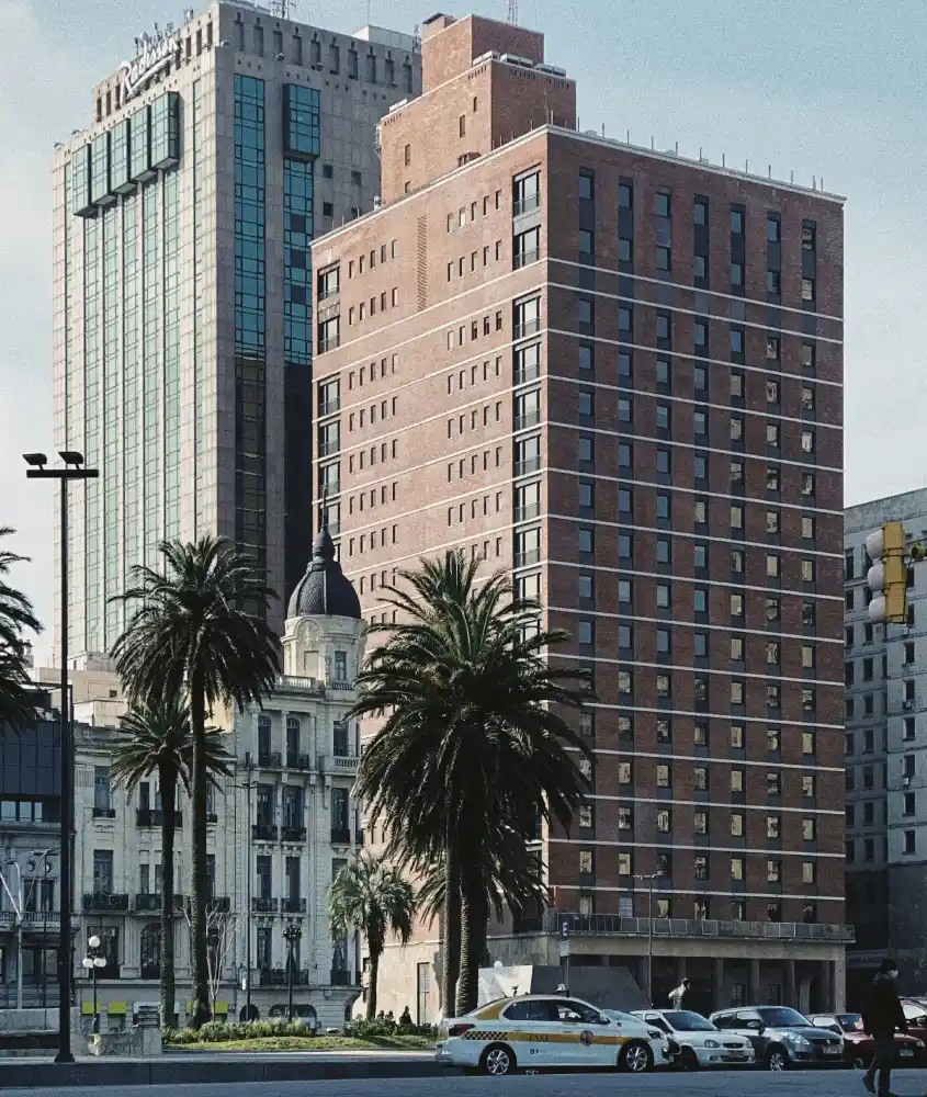 Imponentes fachadas de edifícios no centro de Montevidéu, incluindo o Radisson Montevideo, sob um céu claro, refletindo o estilo arquitetônico moderno da cidade