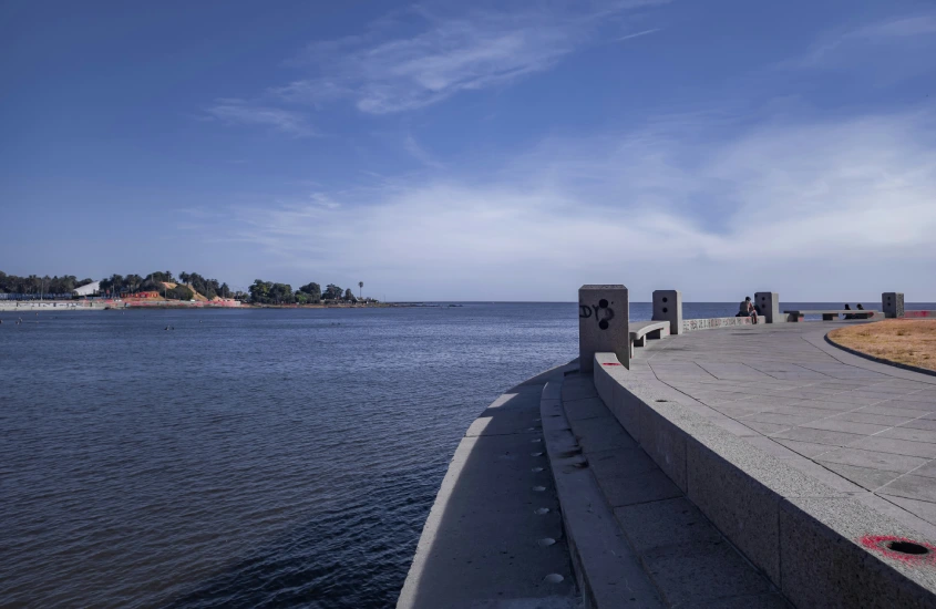 Vista da Rambla de Montevidéu, um calçadão à beira do Rio da Prata, ideal para caminhadas e atividades ao ar livre, com céu azul e o rio ao fundo