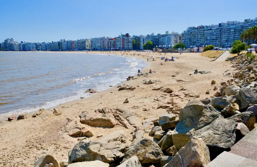 Praia de areia clara da Playa Pocitos, com prédios altos ao fundo, um dos principais pontos de lazer à beira-mar em Montevidéu em um dia ensolarado