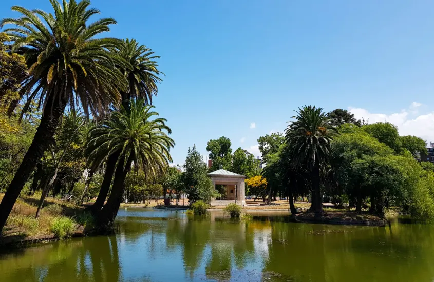 Lago tranquilo rodeado por palmeiras no Parque Rodó, um dos maiores parques de Montevidéu, ideal para relaxar e fazer piqueniques