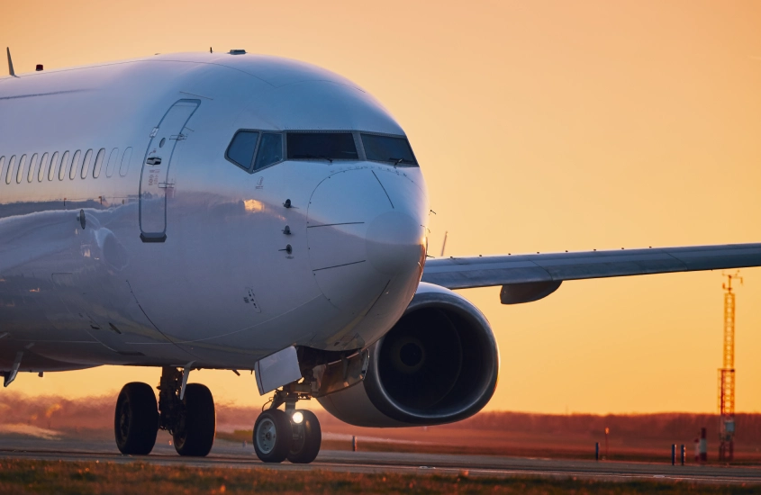 Avião taxiando na pista durante o pôr do sol, representando as opções de transporte aéreo para chegar a Montevidéu com facilidade e conforto