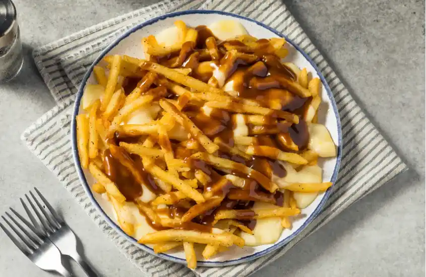 Prato de poutine com batatas fritas, molho gravy e queijo coalho, uma das iguarias mais famosas de Montreal