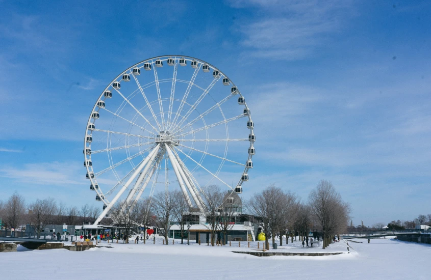 A La Grande Roue de Montreal cercada pela neve, destacando-se contra o céu azul claro, um passeio imperdível para ver a cidade do alto