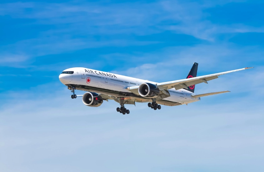 Aeronave da Air Canada se aproximando para pouso sob um céu azul, representando as opções de transporte aéreo para chegar ao Canadá