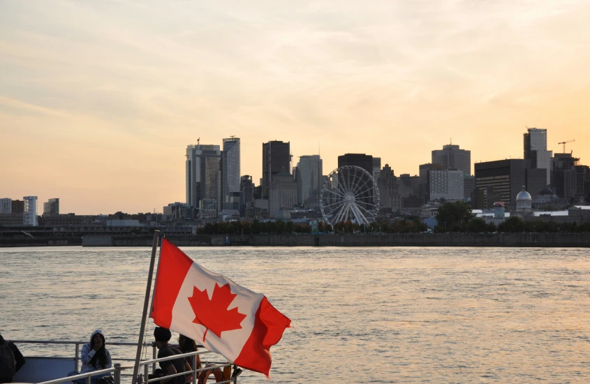 Vista panorâmica da cidade de Montreal ao pôr do sol, com a bandeira do Canadá e a roda-gigante La Grande Roue ao fundo