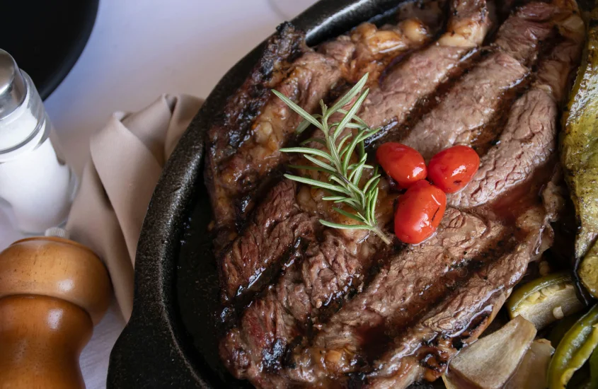 Um prato suculento de carne grelhada com ramos de alecrim e pimentas, típico da culinária irlandesa