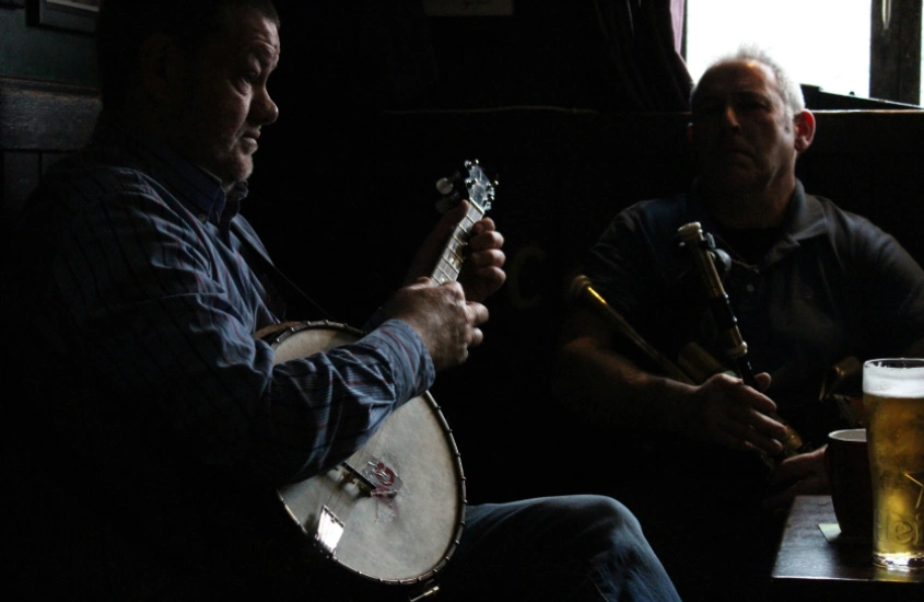 Dois músicos tradicionais tocando em um pub irlandês, mantendo viva a rica cultura musical do país