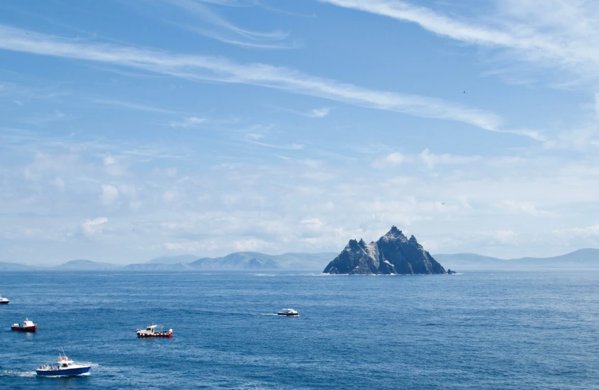 Vista do oceano com barcos próximos a Skellig Michael, destacando a beleza natural e o turismo da região