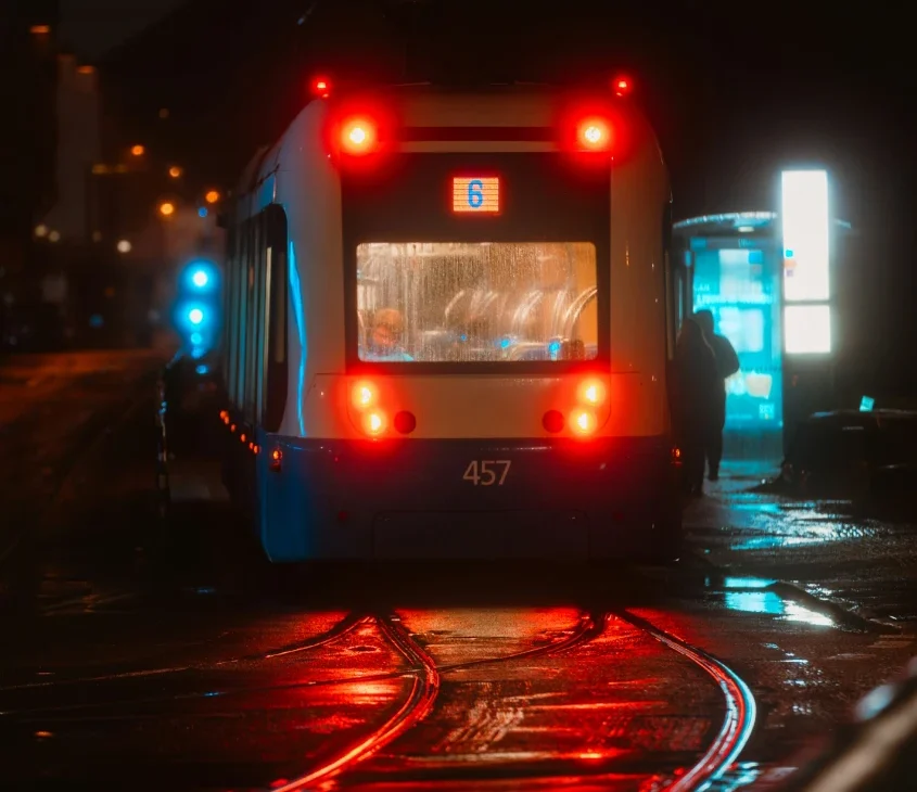 Tram sueco em uma noite chuvosa, com luzes refletidas nas ruas molhadas de uma cidade da Suécia.