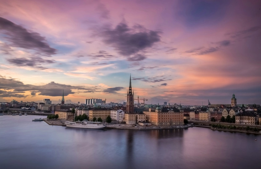 Vista panorâmica do centro histórico de Estocolmo ao entardecer, com o céu em tons de rosa e laranja.