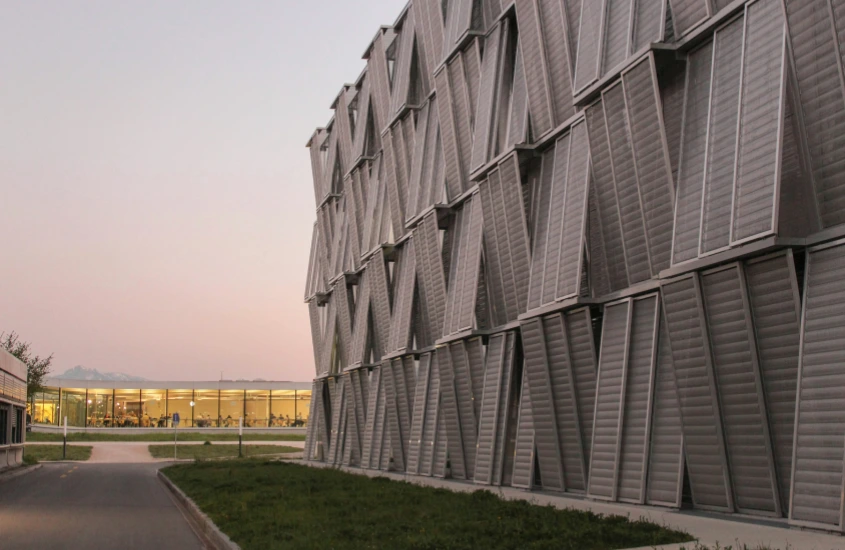 Fachada de um prédio moderno com janelas geométricas em destaque durante o pôr do sol