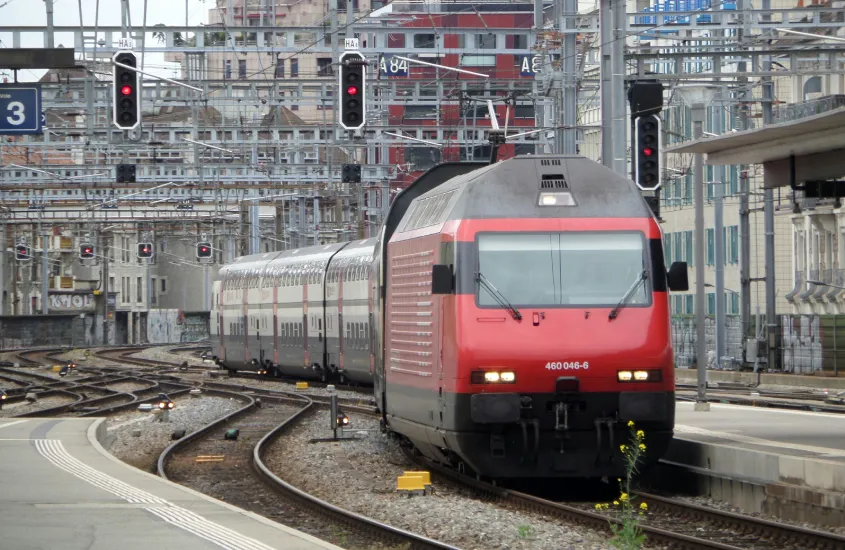 Trem vermelho na estação ferroviária, cercado por sinais e trilhos intrincados