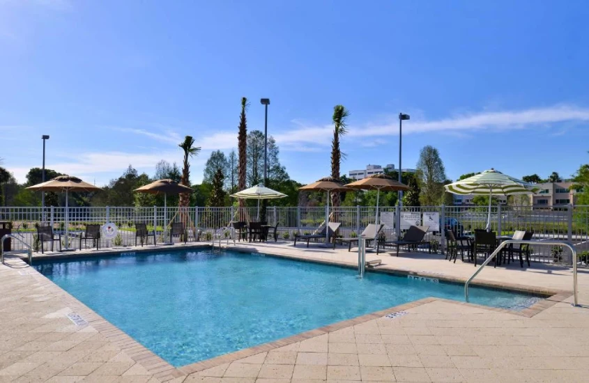 Piscina no Hampton Inn & Suites Downtown South Orlando, cercada por árvores e espreguiçadeiras