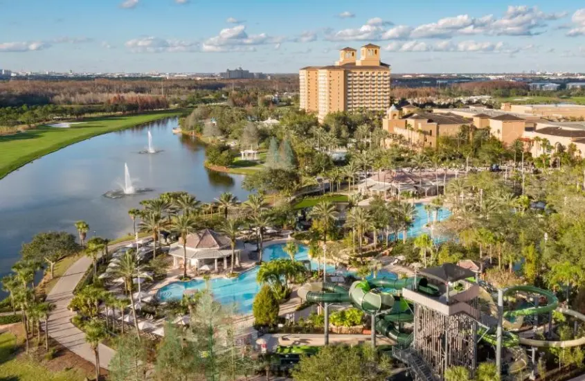 Vista aérea das piscinas e área verde do The Ritz-Carlton Orlando, Grande Lakes, com lago ao fundo e várias áreas de lazer.