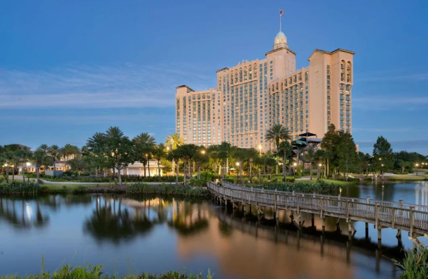 JW Marriott Orlando, Grande Lakes, visto de frente com uma ampla área de lazer e piscinas cercadas por palmeiras e um lago.