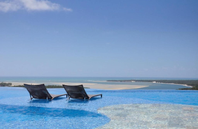 Duas espreguiçadeiras com vista para o mar, na piscina de borda infinita do Gungaporanga Hotel, em Alagoas.