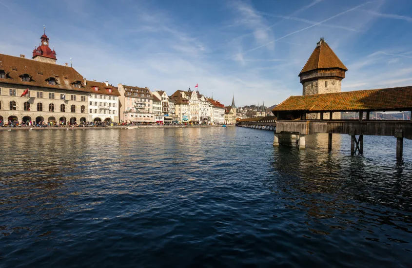 A icônica Ponte da Capela sobre o Rio Reuss em Lucerna, com edifícios históricos e o céu azul ao fundo