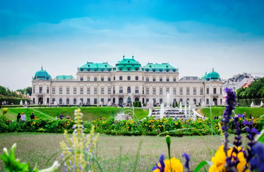 Palácio Belvedere em Viena, com jardins floridos e fontes no primeiro plano, em um dia claro de verão