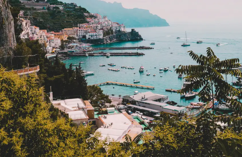 Vista de uma cidade litorânea na Costa Amalfitana, Itália, com o mar cercado por montanhas e casas coloridas dispostas no penhasco