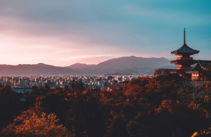 Uma vista panorâmica da cidade de Kyoto, no Japão, ao entardecer, com um templo tradicional ao primeiro plano