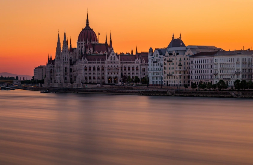 O Parlamento de Budapeste iluminado ao pôr do sol, refletindo no rio Danúbio, um dos lugares mais românticos da Europa