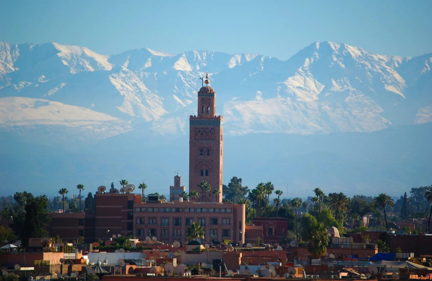 A torre do minarete da Mesquita Koutoubia em Marrakech se destaca contra as montanhas cobertas de neve ao fundo