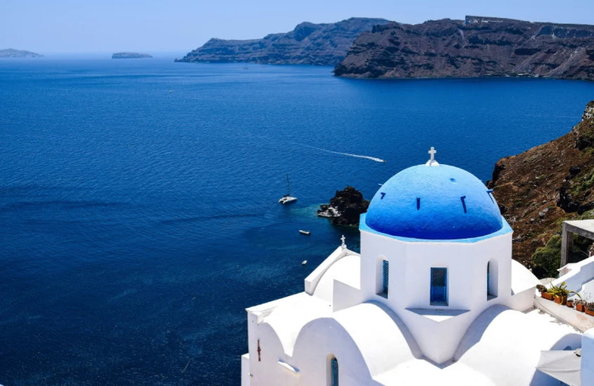 Igreja com cúpula azul em Santorini, Grécia, destacando a beleza do lugar de um dos lugares mais românticos do mundo