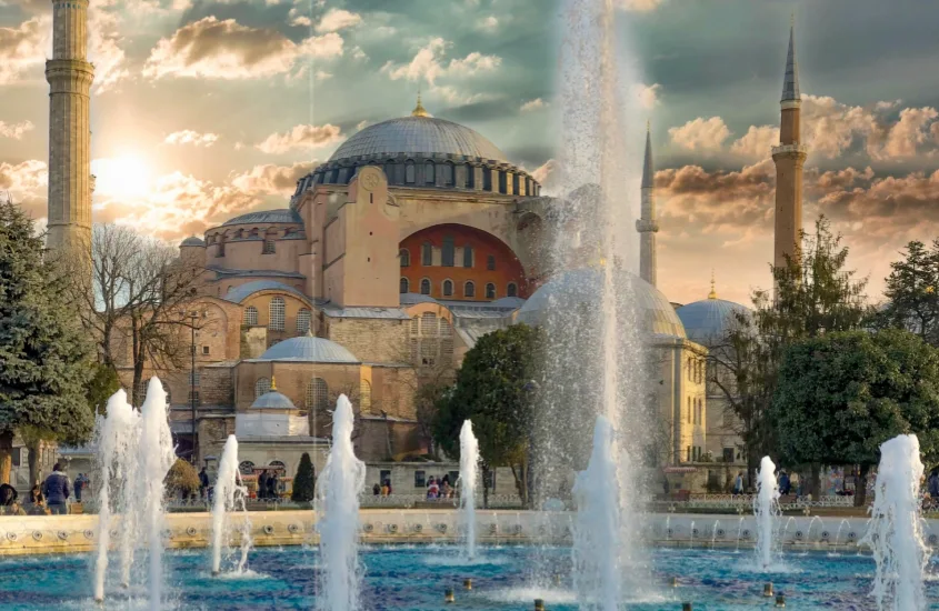 Hagia Sophia, uma das principais atrações de Istambul, com suas cúpulas e minaretes ao fundo e a fonte do Sultanahmet Park em destaque, proporcionando uma vista icônica