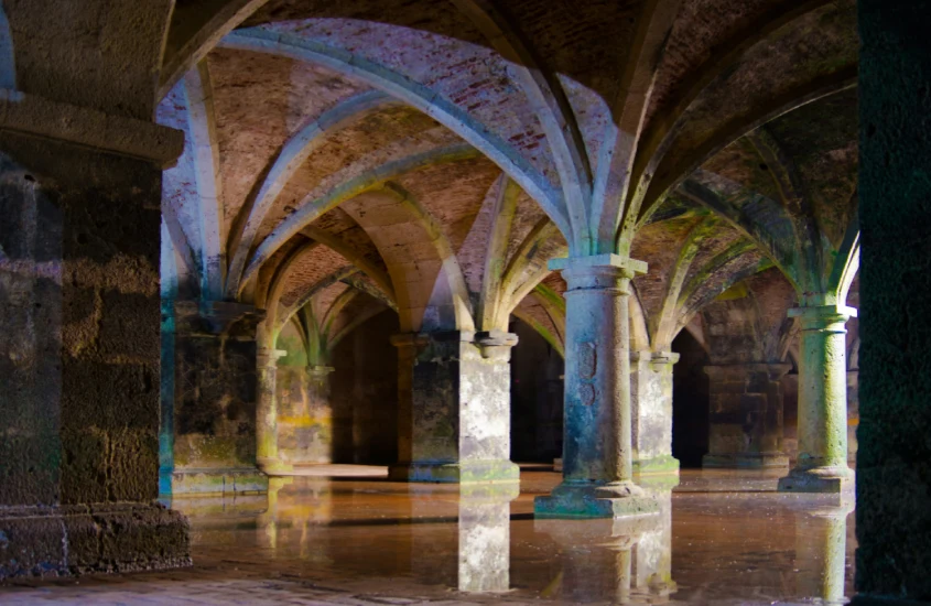 Antiga cisterna de pedra com arcos imponentes refletida na água, em uma construção subterrânea histórica em Istambul