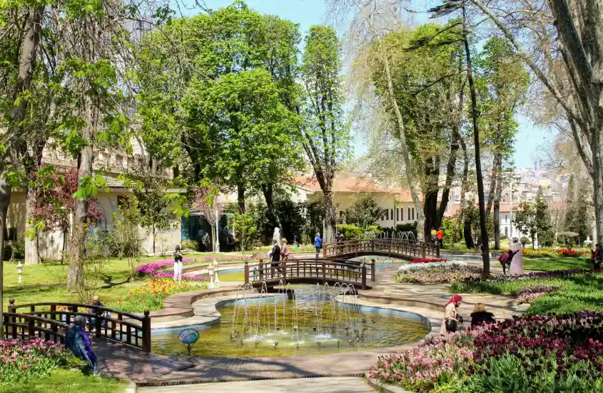 Jardim verdejante com fontes e flores coloridas, cercado por caminhos e pequenas pontes no Palácio de Topkapi, em Istambul