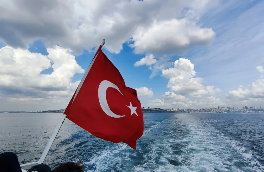 Bandeira da Turquia tremulando ao vento em uma embarcação no Estreito de Bósforo, com vista panorâmica de Istambul