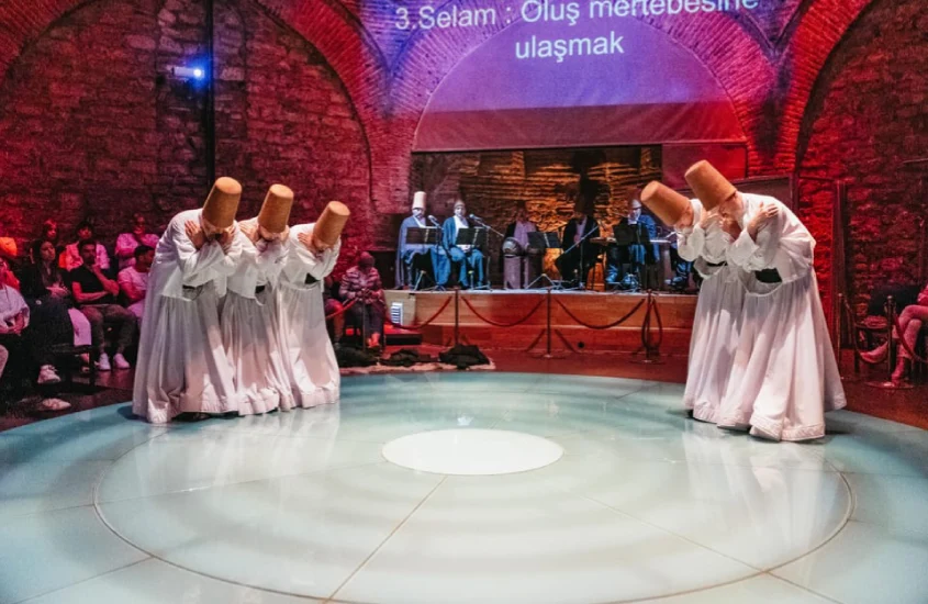 Cerimônia de dança dos dervixes rodopiantes em um salão tradicional em Istambul, com músicos ao fundo e público assistindo