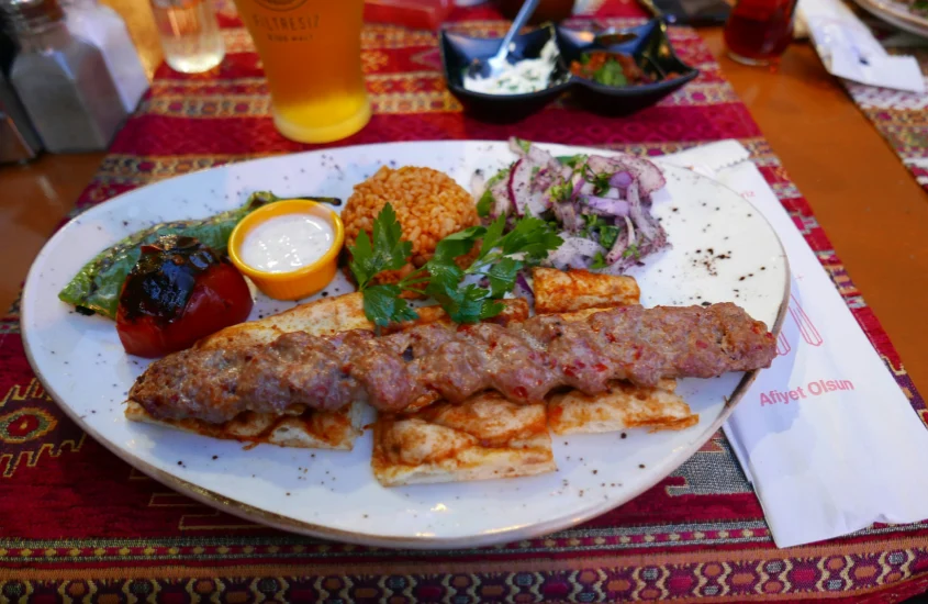 Prato tradicional turco com kebab, arroz, salada e molho, servido em um restaurante típico em Istambul