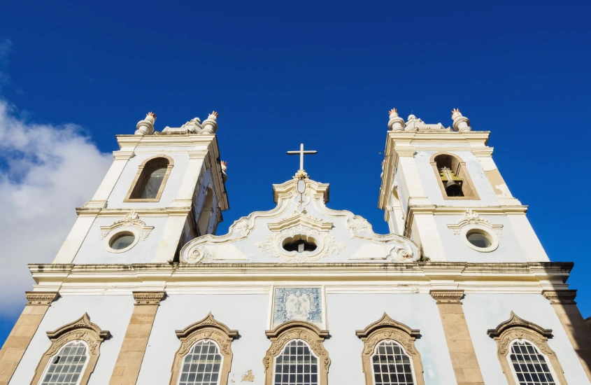 Fachada da Igreja do Bonfim em Salvador, com detalhes em branco e azul, realçada pelo céu azul sem nuvens.