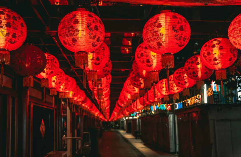 Lanternas vermelhas decoradas com caracteres chineses penduradas em um corredor, iluminando o espaço com uma atmosfera festiva.