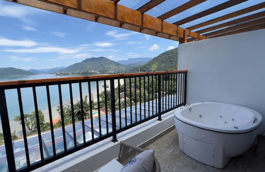 Jacuzzi em uma varanda com vista para o mar e montanhas, criando um ambiente ideal para relaxar.