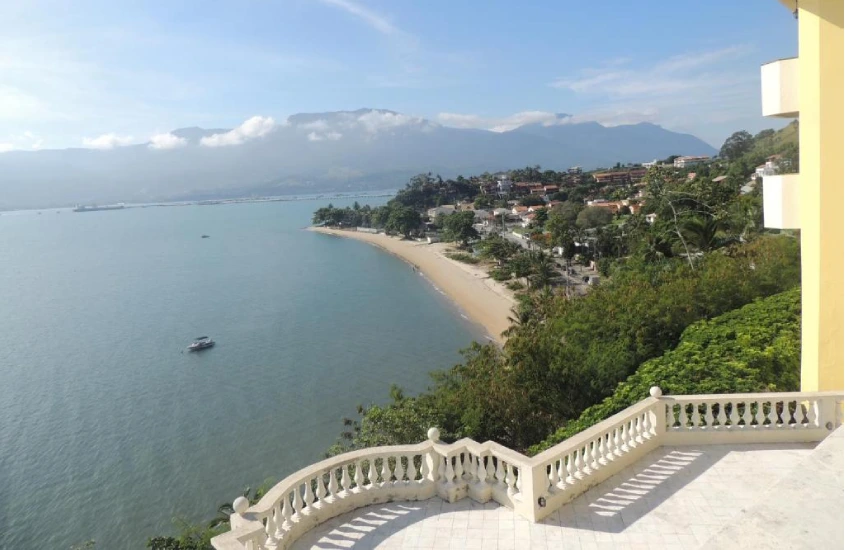 Terraço com vista panorâmica para a praia e o mar, cercado por uma balaustrada clássica.