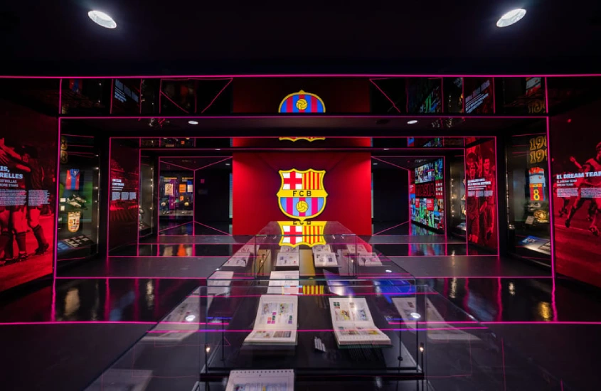 Museu esportivo com prêmios expostos e escudo iluminado no fundo