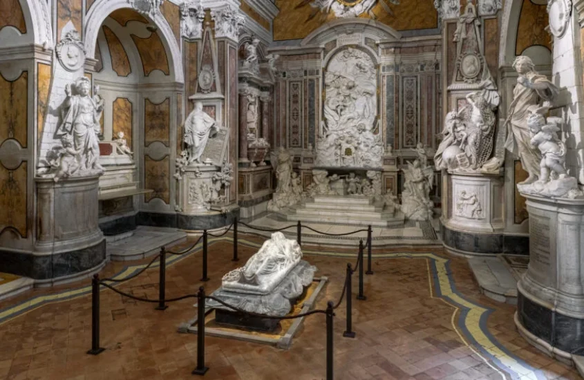 Interior da Capela Sansevero, com esculturas detalhadas em mármore, incluindo a famosa escultura do Cristo Velado no centro.