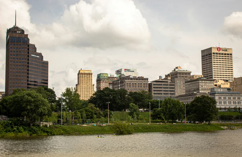 Paisagem urbana de Downtown Memphis vista do parque à beira do Rio Mississippi, com prédios emblemáticos e áreas verdes em primeiro plano.