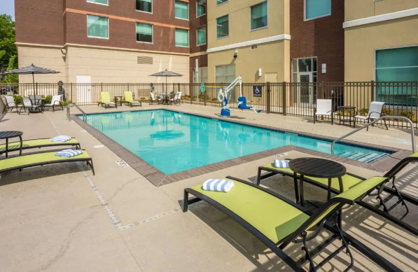 Piscina ao ar livre, cercada por espreguiçadeiras com almofadas verdes, em um lugar onde ficar em Memphis.