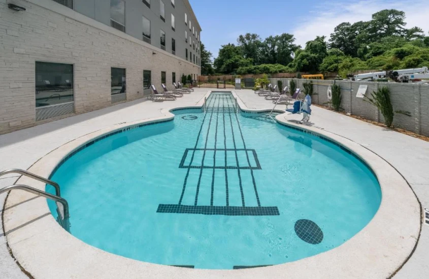 Piscina criativa em formato de guitarra no hotel Holiday Inn Express & Suites Memphis Arpt Elvis Presley Blvd, com detalhes de cordas em mosaico.