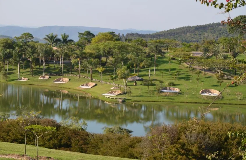 Em um dia de sol, lago de um dos hotéis cinco estrelas no interior de SP com sofás e área verde ao redor