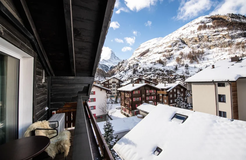 Vista de uma varanda aconchegante no Tradition Julen Hotel, cercado por neve e chalés típicos.