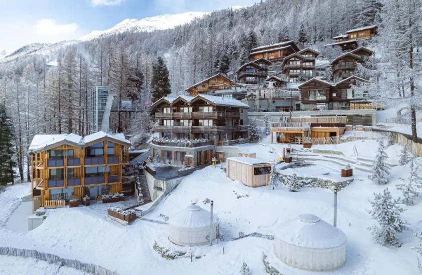 Complexo do CERVO Mountain Resort em Zermatt, com suas modernas cabanas alpinas cercadas por neve.