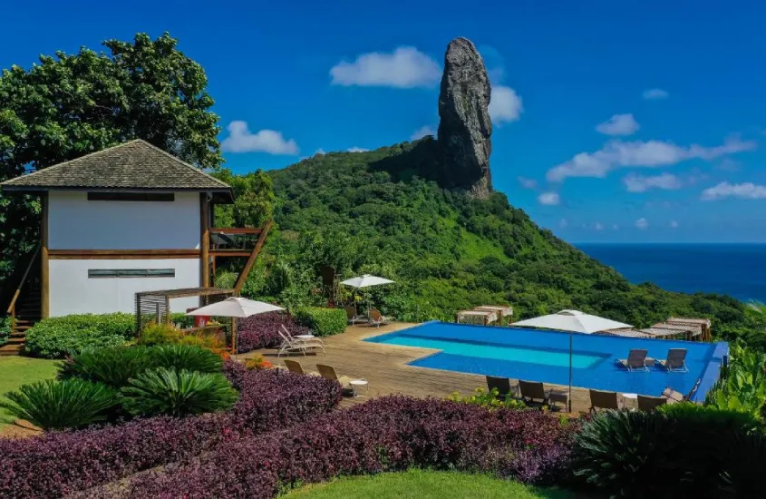 Piscina da Pousada Morena, com vista para a icônica Pedra do Pico, rodeada por plantas e espreguiçadeiras.