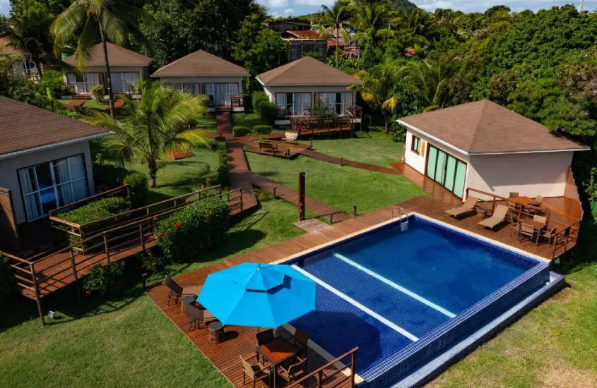 Piscina rodeada por espreguiçadeiras de madeira da Pousada Lua Bela, com vista para a vegetação tropical e ambiente ensolarado.