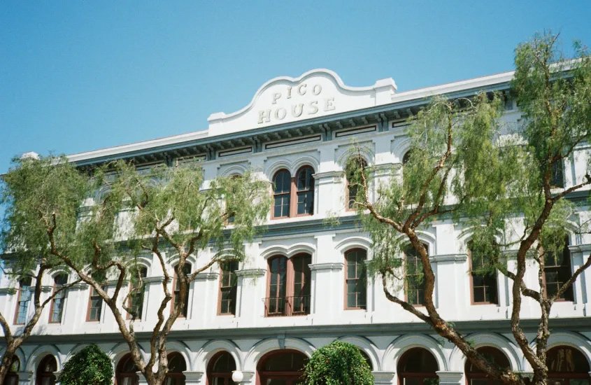 Fachada do Pico House, edifício histórico de Los Angeles com arquitetura clássica e árvores na frente.