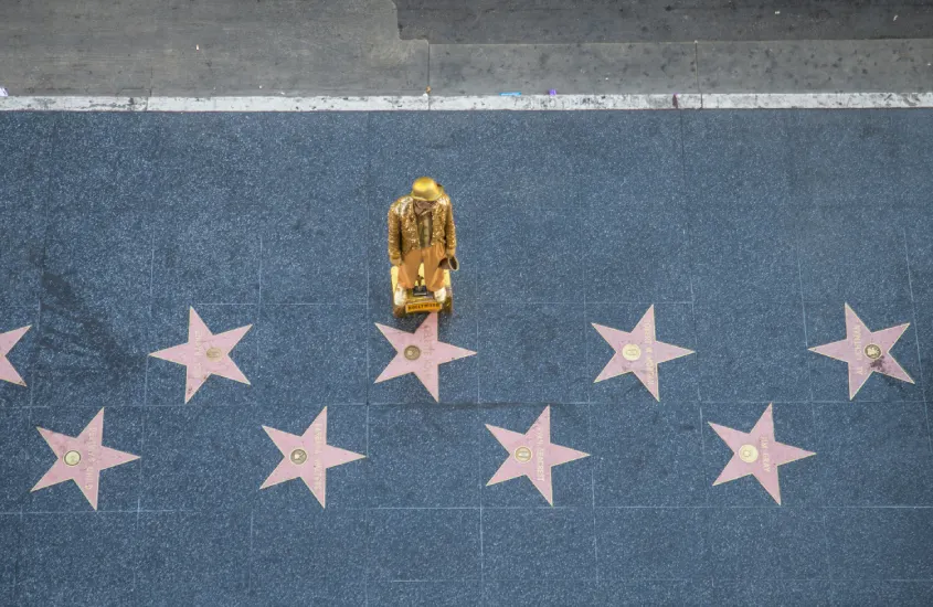 Estrelas da Calçada da Fama de Hollywood com uma estátua dourada de artista de rua no centro.